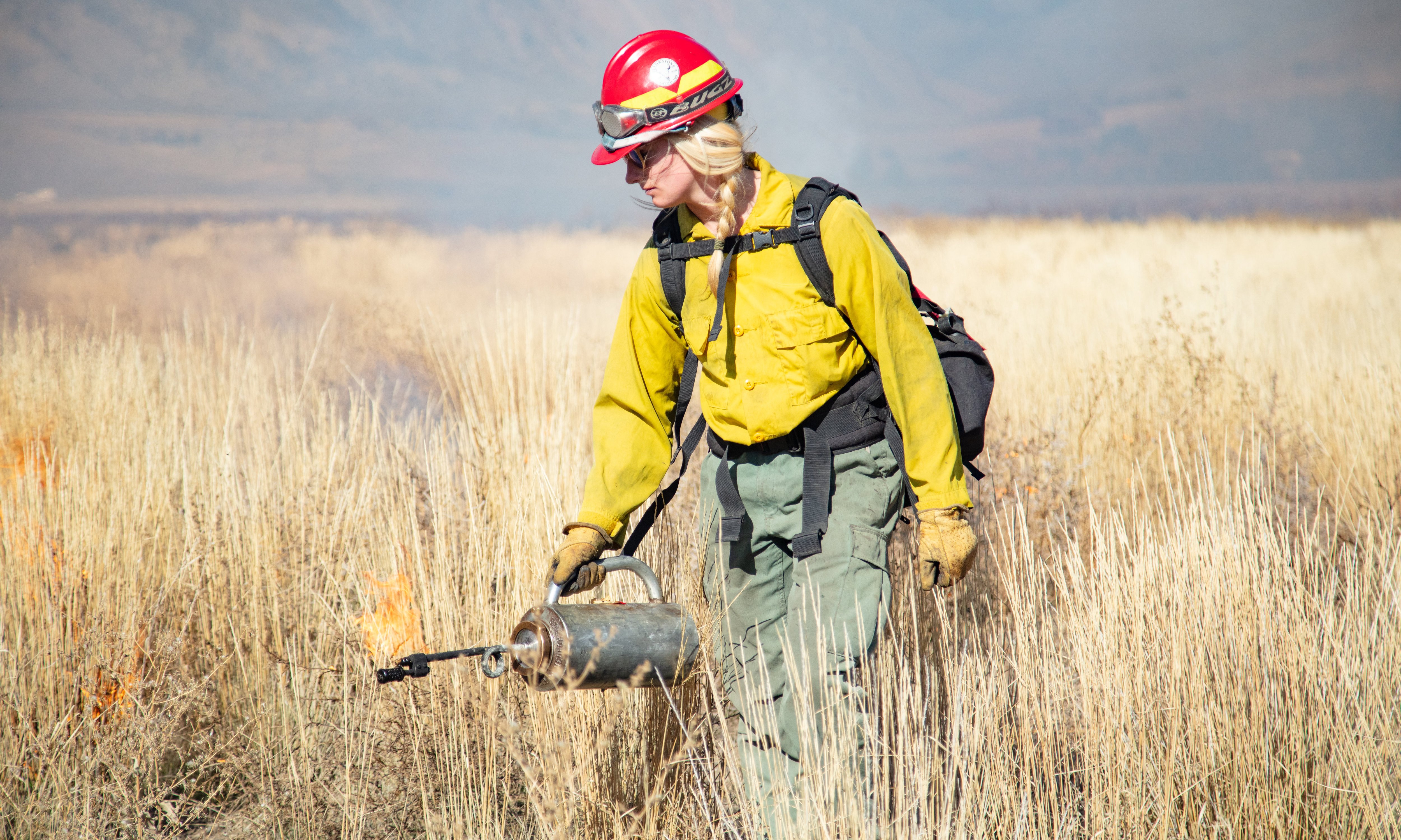 A firefighter carrying a drip torch