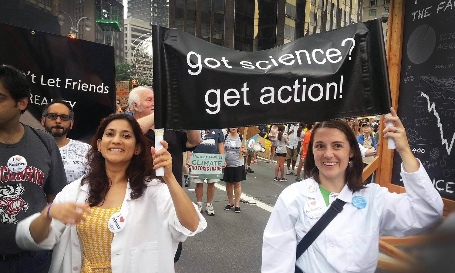 Two scientists holding a sign that says "Got Science? Get Action!"