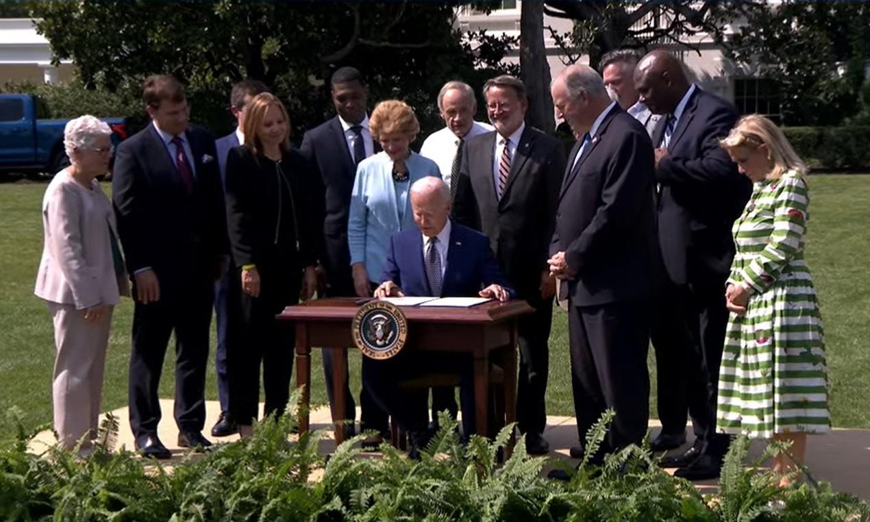 President Joe Biden signing something outdoors.