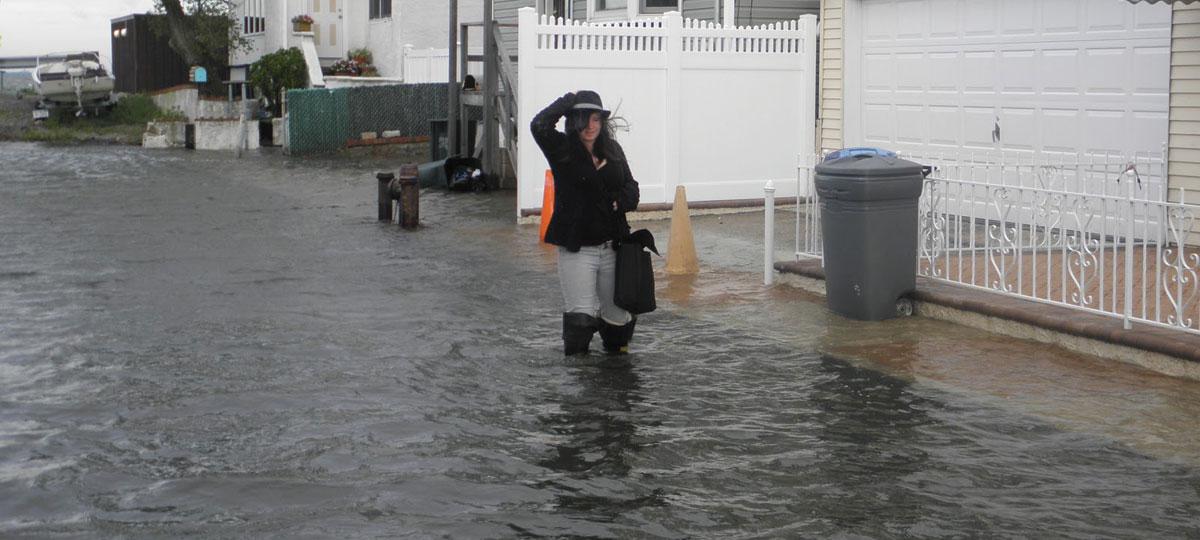 Girl wading through tidally flooded street in Jamaica Bay, New York