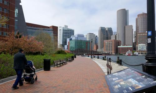 Sidewalk along Boston Harbor with view of city skyline