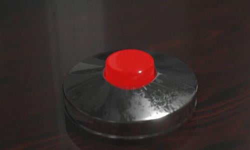 Red nuclear launch button on a wooden desk