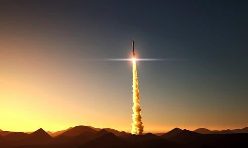 Missile launch above a mountain range at sunrise