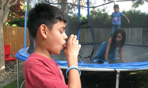 Boy using inhaler while playing with other kids