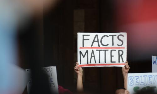 Hands holding up a sign that reads facts matter