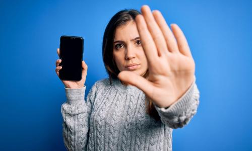 Woman holding phone with hand up 