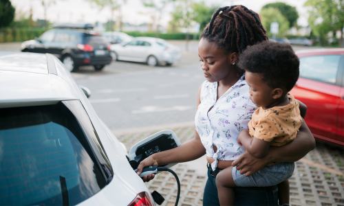 A woman with a toddler is charging an electric car 