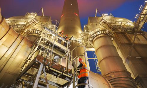 Workers at a coal fired plant climbing a ladder.