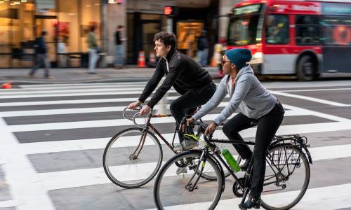 two people biking in LA with bus in background