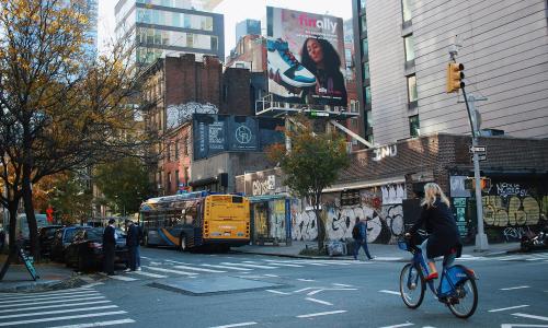 woman riding bike in back of new york mta hybrid bus